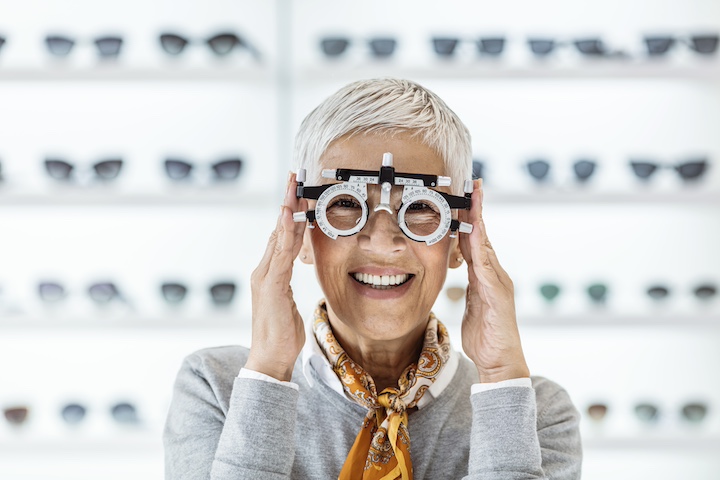 Ältere Dame mit Optiker Brille Hintergrund Brillenregal